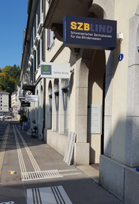 Weisse Leitlinien führen in den Hauseingang des SZBLIND an der Schützengasse.